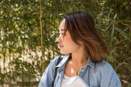 A beautiful college student carrying books at the campus.の写真素材