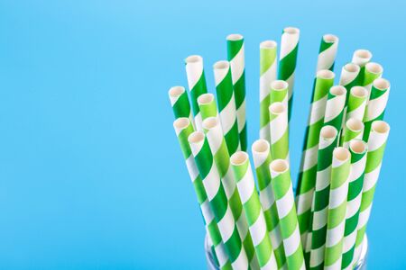 Green and white striped paper straws on blue backgroundの写真素材