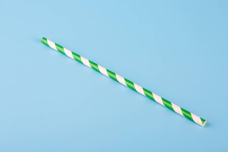 Green and white striped paper straw on blue backgroundの写真素材