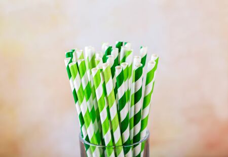 Green and white striped paper straws in a glassの写真素材