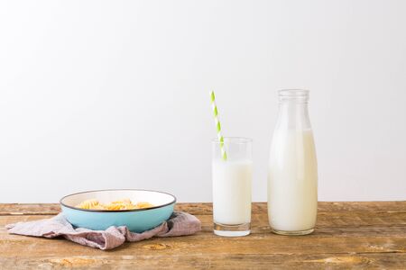 A glass of milk with milk bottle and cookies on wooden table