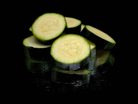 green zucchini slices on a black background water dropsの写真素材