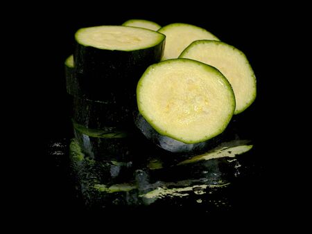 green zucchini slices on a black background water dropsの写真素材