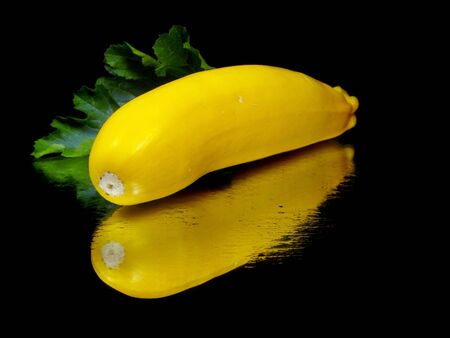 yellow zucchini with leaf on a black background with water drop 
の写真素材