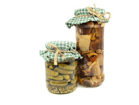 Glass jars of preserved mushrooms and pickles on a white backgroundの写真素材