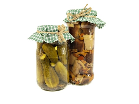 Glass jars of preserved mushrooms and pickles on a white backgroundの写真素材