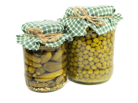 Glass jars with pickled cucumbers and canned green peas on a white background 
の写真素材