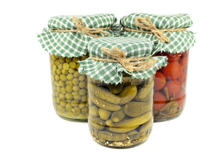 Glass jars with pickled cucumbers, tomatoes and canned green peas on a white background 
の写真素材