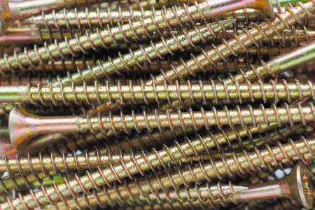 Background of screws, long and yellow. reduced contrast. Hardware, fasteners, materials for...