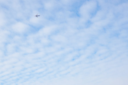 The passenger airplane is flying far away in the blue sky and white clouds. Aircraft in the air....