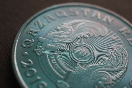 Translation: Kazakhstan. Kazakh 50 tenge coin with the country emblem and focus on shanyrak. close-up. Green tinted background or wallpaper for Kazakh economy or state. Macroの写真素材