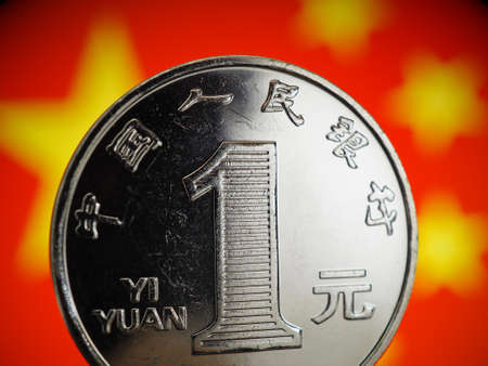Chinese money. 1 yuan coin on the background of the flag of the China PRC close-up. Economy, national currency exchange rate, devaluation, trade war, one belt one road strategy. Macroの写真素材