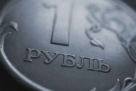 Translation: ruble. A fragment of the Russian coin in 1 one ruble. The name of the national currency of Russia close-up. News about economy, money and banks. Gray blue background or wallpaper. Macroの写真素材