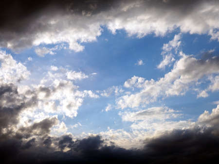 Blue sky and white clouds framed by dark thunderclouds after a thunderstorm. Dramatic impression...