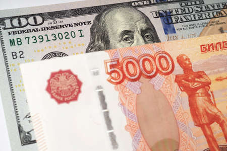 Fragments of Russian and American paper money closeup. ruble and dollar. A banknote of 5000 rubles and a note of 100 dollars. Illustration about exchange rate. News of economy and finance. Macroの写真素材