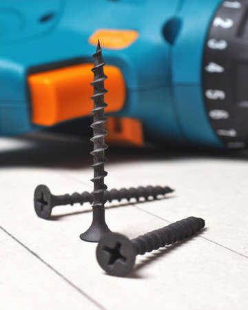 Screwdriver and screws lie on a sheet of drywall. The gypsum sheet is marked with a pencil. Building...