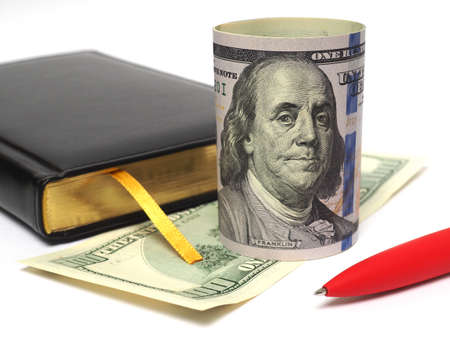 Banknotes 100 dollars stand and lie beside the diary. Items on a white background. close-up