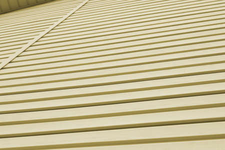 The striped surface of the plastic siding and piece of cornice. Construction and repair of buildings. Light olive background or wallpaper. Backdrop on the theme of building materials and technologiesの写真素材