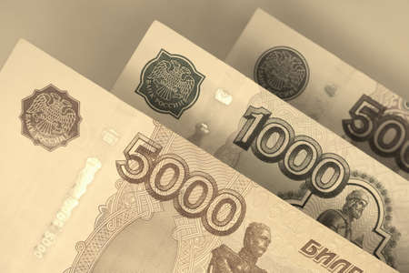 Russian banknotes 5000, 1000, and 500 rubles close up. Light brown or yellow background or wallpaper about economy and money of Russia. Sepia. Macroの写真素材