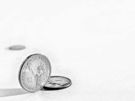 Black and white background on the theme of USA economy, finance or banks with space for text. An American 1 one dollar coin stands on its edge. US coins backdrop with copy-space. Macroの写真素材
