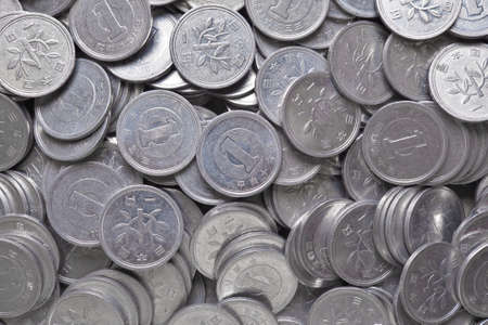 A scattering of many Japanese coins in 1 yen. Gray or blue background or wallpaper. News about the economy, finances and interest rate of the central bank of Japan. view from above. close-upの写真素材