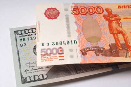 The Russian banknote of five thousand rubles hangs over the American banknote of one hundred...