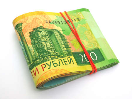A rolled up bundle of Russian banknotes of 200 rubles lies on a white paper background. Denominations are connected by an elastic band. News of microcredit organizations about loans and depositsの写真素材