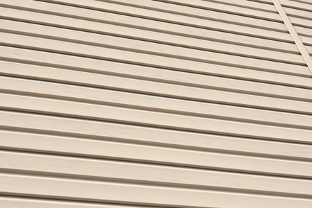 The striped surface of the plastic siding. Construction and repair of buildings. Light yellow background or wallpaper. Building material and technologies. Wall covering with protective materialsの写真素材