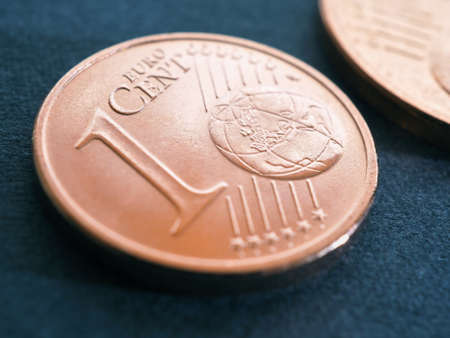 A one euro cent coin lies on a dark blue-gray surface. Money close-up. Illustration on economic or financial theme. The withdrawal of small coins from circulation and the rounding of price tags. Macroの写真素材