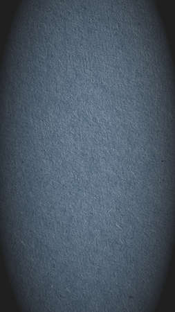 The surface of slate gray cardboard. Paper texture with cellulose fibers. Glamorous mobile phone wallpaper with vignetting. Vertical paperboard background with a generic gray tint. Macroの写真素材