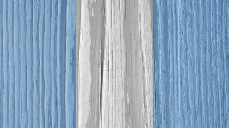 The flag of Guatemala on a dry wooden surface, cracked with age. It seems to flutter in the wind. Light pale faded paint. background or wallpaper. Annual rings of old wood. hard sunlight with shadowsの写真素材