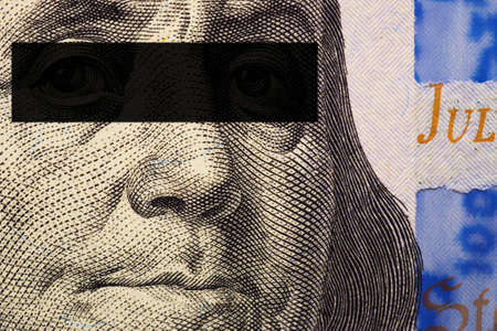 Franklin's face close-up with a black stripe of censorship on his eyes on a fragment of a 100 dollar bill of the new sample. Offshore, off books money under the table, corruption, bribe. Macroの写真素材