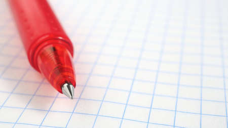 Background on the theme of the new school year with place for text. Pen lies on a grid notebook sheet close-up. Light backdrop for September 1 with copy-space. Starting study and education. Macroの写真素材