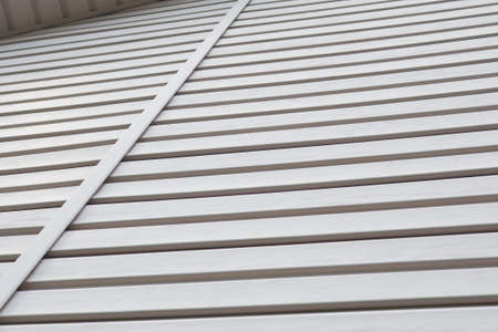 Striped plastic siding surface and piece of cornice. Construction and renovation of buildings. Light...