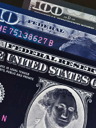 US banknotes of 1, 10 and 100 dollars close-up. Vertical spectacular inverted photo about taxes and money laundering in the USA. Macroの写真素材