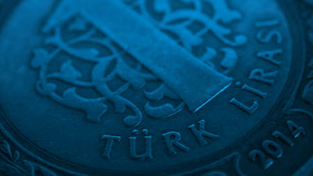 Translation: Turkish lira. Fragment of Turkish 1 one lira coin close-up. National currency of Turkey. Blue tinted money wallpaper. Background for news about economy or finance. Macroの写真素材