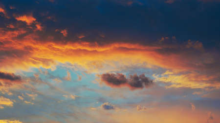 Cloudy sky at sunset. Dark blue and yellow natural background or wallpaper. The rays of the setting...