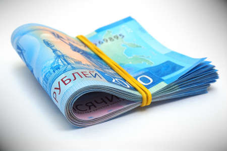 Rolled up bundle of Russian 2000 rubles banknotes. Lies on a white paper surface. The bills are tightened with an elastic band. Bank loans, deposits and interests. Vignetting. expressive illustrationの写真素材