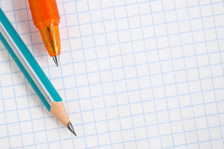 Wooden pencil and orange pen lie on a blank notebook sheet close-up. Light background on the topic of schooling with place for text. White backdrop for the new school year with copy-space. Macroの写真素材