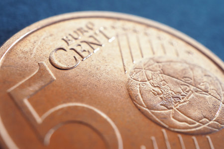 A 5 euro cent coin lies on a dark blue-gray surface. Money close up. Illustration for economic, financial, banking news. The rounding of price tags. Macroの写真素材