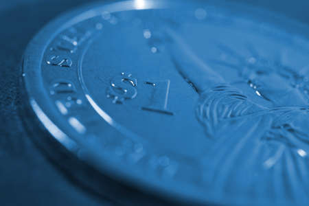 US one dollar coin close-up. Dark blue tinted background or wallpaper. American money, economy,...