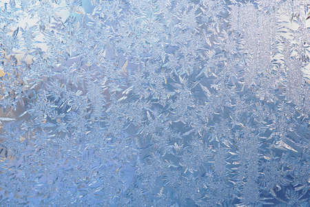 Winter light white and blue background or wallpaper. Drawing of crystals of ice and frost on the...