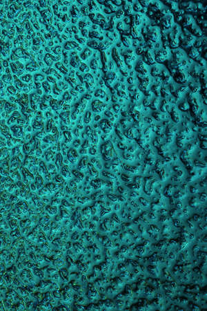 Bright teal winter background. The surface of ice frozen on the window pane. An abstract pattern...