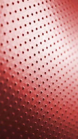 Tinted red metal background with bright saturated color. Dark vertical wallpaper for mobile. Perforated aluminum surface with many holes. Their ranks go into the distance and form a perspective. Macroの写真素材