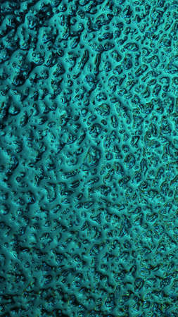 Bright teal winter background. The surface of ice frozen on the window pane. An abstract pattern...