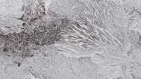 Ice on a window glass in winter. The pattern of crystals looks like a magical plant. Weather...