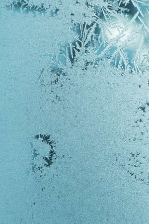 Frozen and misted window glass. Abstract winter teal background with ice crystals. light cyan...