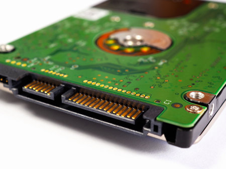 Hard drive HDD of a computer or laptop. Fragment close-up. Green circuit board PCB lies on a white...