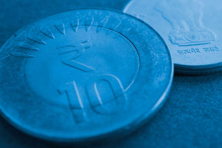 Translation: Truth Alone Triumphs. Two Indian coins lie on textured surface. 10 rupee coin with the...