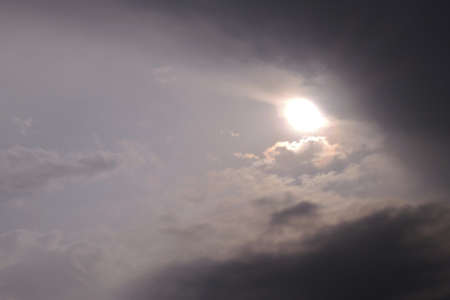 The sun looks out from behind the clouds before a thunderstorm. Dark gray heavy stormy sky. Dramatic...